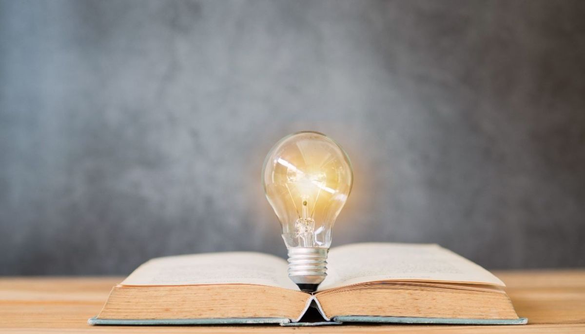 Aufgeschlagenes Buch mit fächerförmig aufgeblätterten Seiten in warmem Licht vor dunklem Hintergrund - symbolisiert Wissenserweiterung, kontinuierliches Lernen und die Vielfalt der Angebote in Fortbildungen und Workshops.