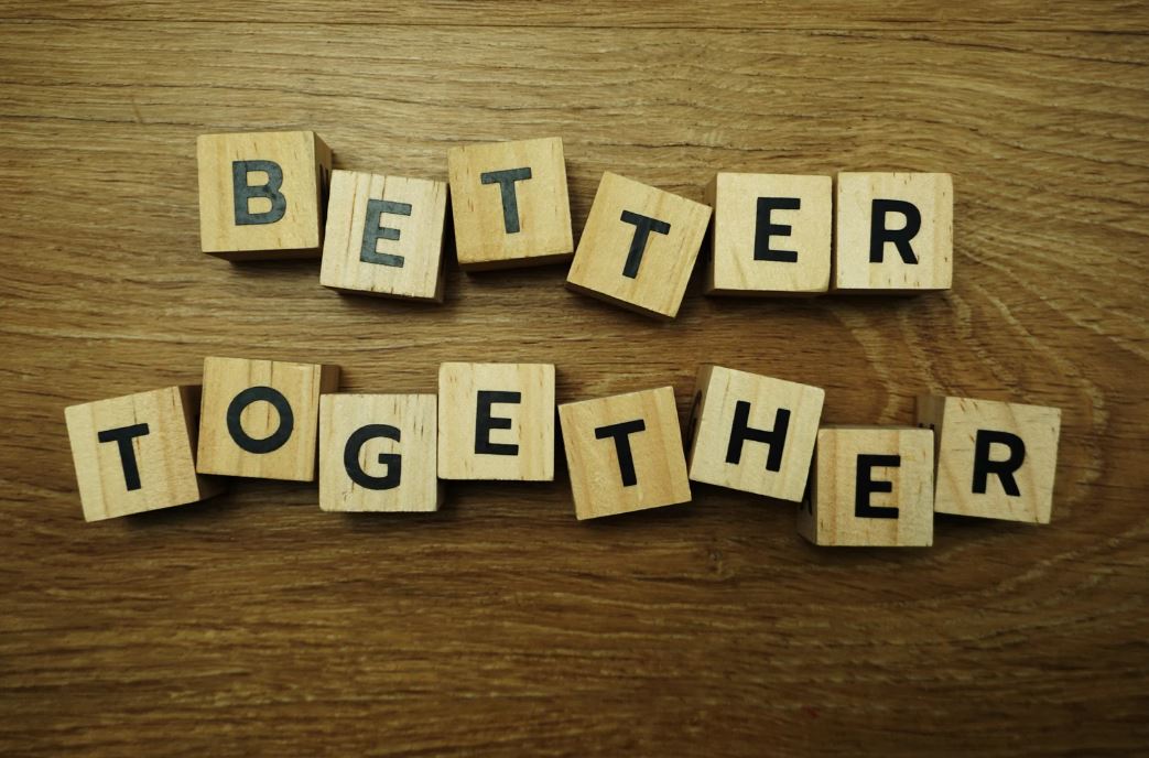 Holzwürfel mit Buchstaben bilden die Worte 'BETTER TOGETHER' auf Holzuntergrund - symbolisiert die Kraft des gemeinsamen Lernens und die gegenseitige Unterstützung in Peer-Learning-Methoden.