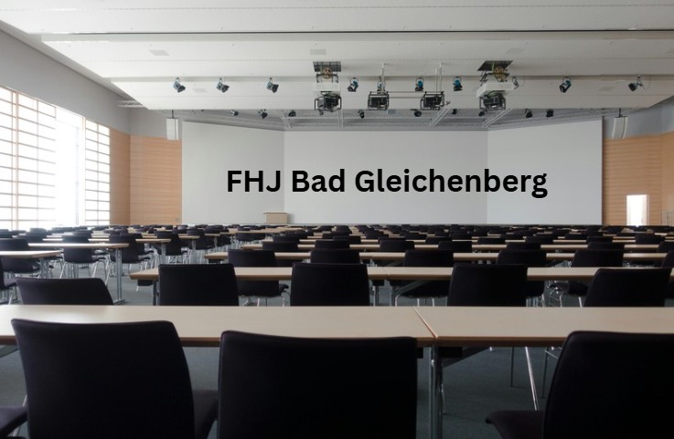 Moderner Hörsaal mit Reihen schwarzer Stühle und Tischen, Beamer an der Decke und technischer Ausstattung - zeigt die technische Infrastruktur und mediale Ausstattung zeitgemäßer Lehrräume.