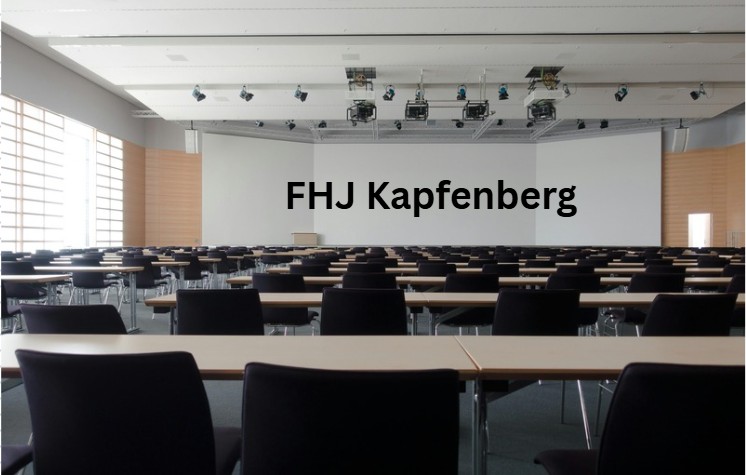 Moderner Hörsaal mit Reihen schwarzer Stühle und Tischen, Beamer an der Decke und technischer Ausstattung - zeigt die technische Infrastruktur und mediale Ausstattung zeitgemäßer Lehrräume.